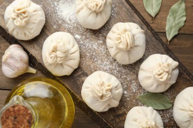 Ahşap masa üzerinde un, yağ ve defne yaprakları ile pişirilmemiş khinkaliler (hamur tatlısı)