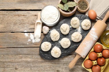 Pişmemiş khinkaliler (hamur köfteleri), un, baharatlar, yumurtalar ve tahta masa üzerinde merdane. Metin için boşluk