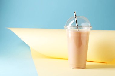Renkli arka planda plastik bardakta lezzetli milkshake, metin için boşluk