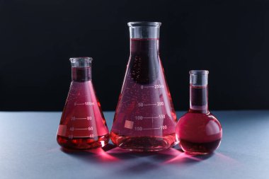 Siyah zemin üzerinde kırmızı sıvı bulunan laboratuvar camları