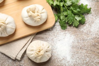 Pişmemiş khinkaliler (hamur tatlısı) ve ahşap masa üzerinde kişniş, düz yatak. Metin için boşluk