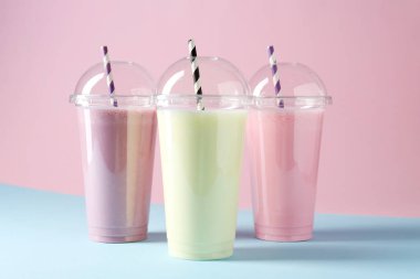 Renkli arka planda plastik bardaklarda lezzetli milkshake.