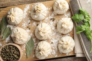 Biber, un, maydanoz ve defne yapraklarıyla ahşap masada pişmemiş khinkaliler (hamur köfteleri)