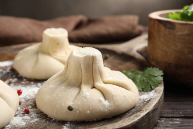Ahşap masada biberli ve maydanozlu pişmemiş khinkaliler (hamur tatlısı), yakın plan.