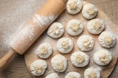 Pişmemiş khinkaliler (hamur köfteleri) ve ahşap masa üzerinde merdane, üst görünüm