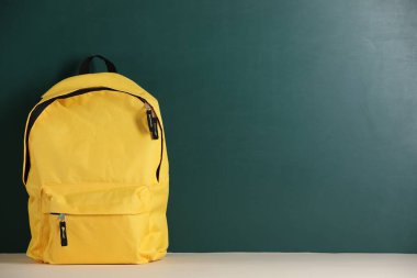 Tahtanın yanındaki masada sarı sırt çantası. Metin için boşluk