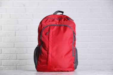 Beyaz tuğla duvara karşı açık mermer masada kırmızı sırt çantası