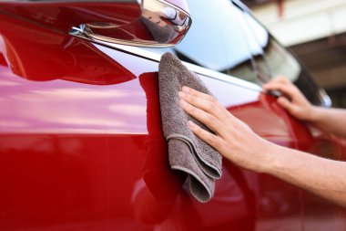 Dışarıdaki gri mikrofiber bez parçasıyla araba silen adam, yakın plan.