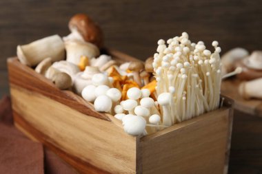 Tahta masadaki sandıkta farklı çiğ mantarlar, yakın plan.