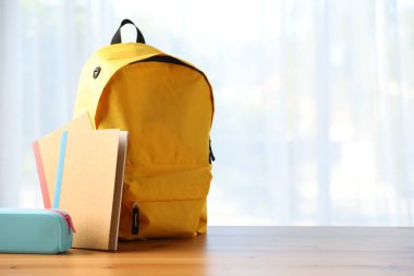 Sırt çantası, not defterleri ve kalem kutusu sınıfın masasında. Metin için boşluk