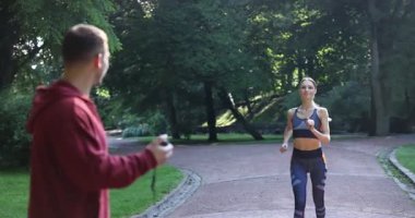 Genç bir kadın profesyonel antrenörle koşuyor ve dışarıda beşlik çakıyor.