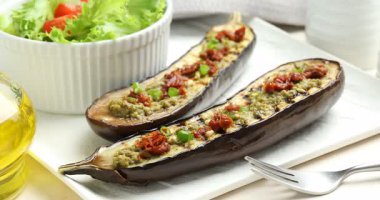 Izgara patlıcan, güneşte kurutulmuş domates, pesto ve salata, yakın plan. Kamera sola hareket ediyor