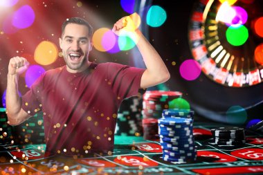 Mutlu kumarbaz zaferi kutluyor. Kumarhane fişleri ve ruletlerle birden fazla kez karşılaşma.