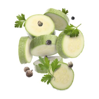 Taze kabak dilimleri, maydanoz ve beyaz arka plana düşen biberler.