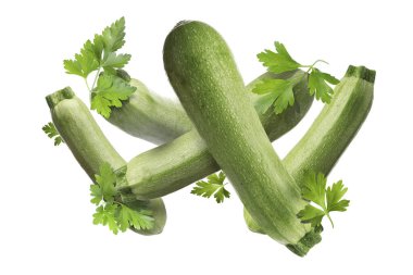 Beyaz arka plana düşen taze kabaklar ve maydanozlar.