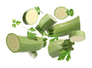 Beyaz arka plana düşen taze kabak ve maydanoz parçaları.