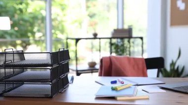 Ev çalışma alanı. Laptop ve kırtasiye malzemeleri pencerenin yanındaki ahşap masada, kamera sola hareket ediyor.