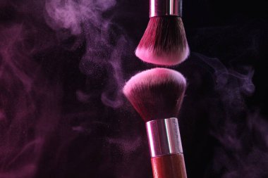 Renkli göz gölgeli makyaj fırçaları siyah arka planda neon ışıkları, yakın plan. Metin için boşluk