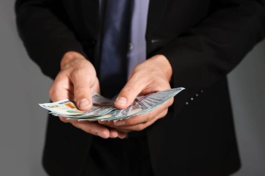 Gri arka planda dolar banknotları olan adam, yakın plan.