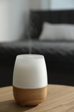 Ahşap masa üzerinde modern aroma lambası, yakın plan.