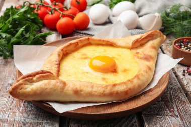 Lezzetli khachapuri peyniri, yumurtası ve diğer ürünleri ahşap masada, yakın plan.