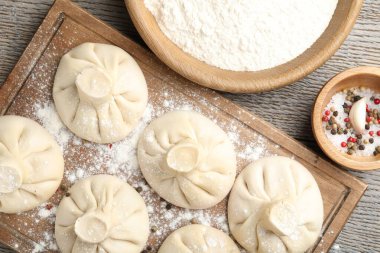 Pişmemiş khinkaliler (hamur tatlısı) ve ahşap masa üzerindeki baharatlar, düz konum