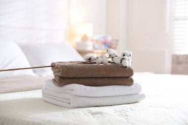 Evdeki çarşafların üzerinde temiz havlular ve pamuk çiçekleri yığını.