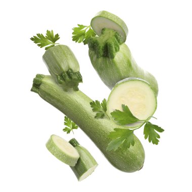 Beyaz arka plana düşen taze kabaklar ve maydanozlar.