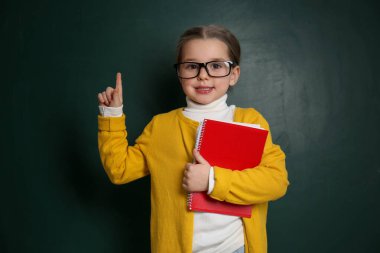 Cute little child wearing glasses near chalkboard. First time at school