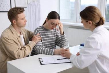 Tüp bebek (tüp bebek). Üreme kliniğine yaptığı ziyarette üzgün çifti destekleyen doktor