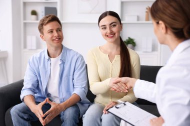 Tüp bebek (tüp bebek). Doktor üreme kliniğinde çiftlerle el sıkışıyor.