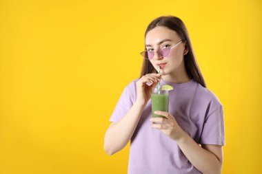 Turuncu arka planda samandan ferahlatıcı içecek içen kadın, mesaj için yer