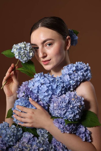 Красивая молодая женщина с гортензией цветы на коричневом фоне