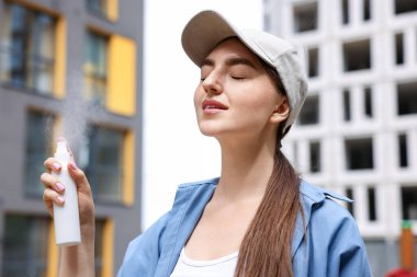 Beyzbol şapkalı gülümseyen kadın dışarıya termal su püskürtüyor.