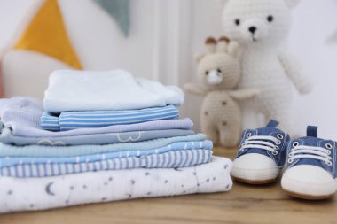 İçerideki ahşap masada temiz bebek kıyafetleri ve ayakkabılar yığını.