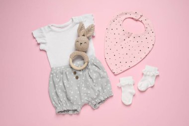 Pembe arka planda şık bebek kıyafetleri ve aksesuarlar.