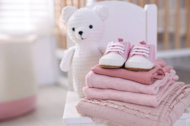 Temiz bebek kıyafetleri, ayakkabılar ve aksesuarlar kapalı bir sandalyede, yakın plan. Metin için boşluk