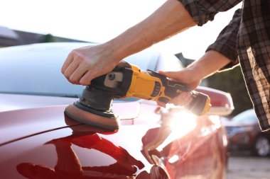 Yörünge cilasıyla araba cilalayan adam, yakın plan.