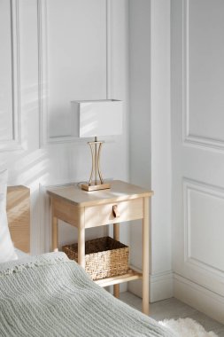 Yatağın yanında lamba olan komodin.