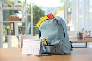 Sınıfta farklı kırtasiye malzemesi ve takvim içeren sırt çantası.