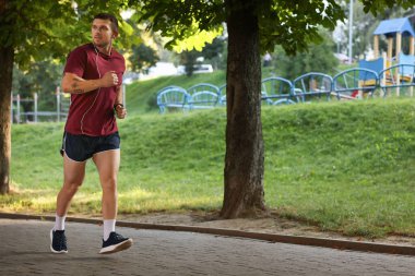 Spor giyimli atletik genç adam dışarıda koşuyor, mesaj için yer var.