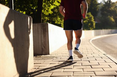 Spor giyimli atletik genç adam dışarı koşuyor, yakın plan.