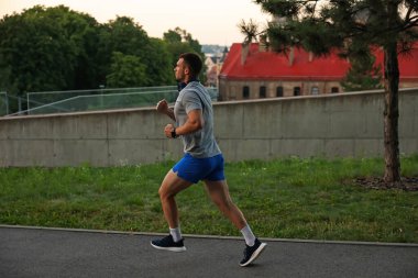 Spor giyimli atletik genç adam dışarıda koşuyor.