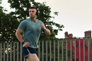 Spor giyimli atletik genç adam dışarıda koşuyor, mesaj için yer var.