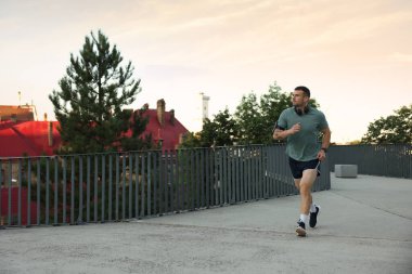 Spor giyimli atletik genç adam dışarıda koşuyor, mesaj için yer var.