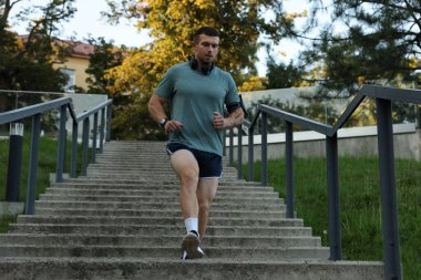 Spor giyimli atletik genç adam merdivenlerden aşağı koşuyor, alçak açılı.