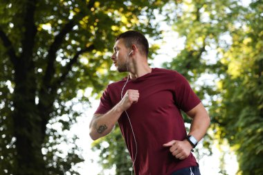 Spor giyimli atletik genç adam dışarıda koşuyor.