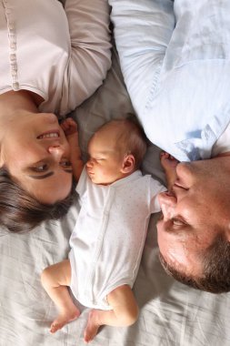 Anne ve baba yeni doğmuş bebekleriyle evde yatıyorlar.