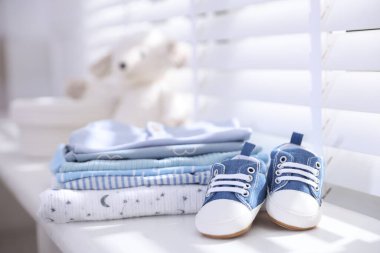 Temiz bebek kıyafetleri ve pencerenin pervazında ayakkabılar, yakın çekim.