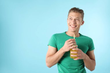 Meyve suyu ve açık mavi arka planda saman içen adam, metin için boşluk